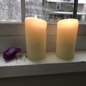Two white pillar candles set in a window