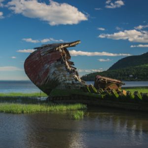 Wooden ship hull jutting improbably out of a placid river landscape