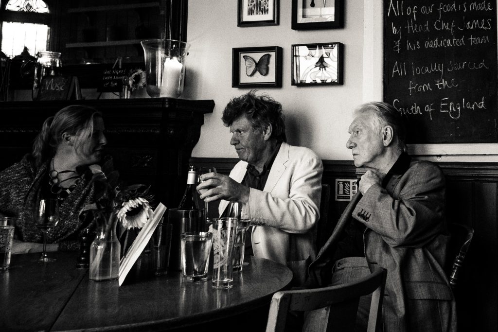 Three people sitting at a round table, with beers