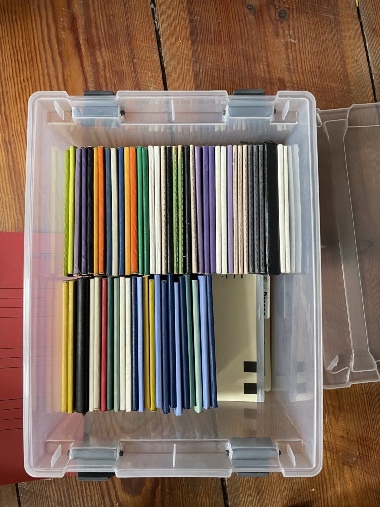 Plastic bin neatly stacked with colored notebooks