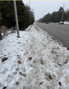 View of a very snowy, icy sidewalk stretching into the distance