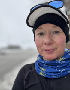 Person wearing outdoor gear, with a gray sky in the background